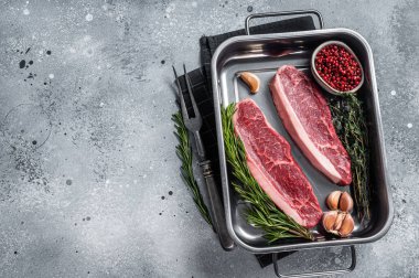 Çiğ sığır filetosu ya da tepside otlu biftek. Gri arka plan. Üst Manzara. Boşluğu kopyala.