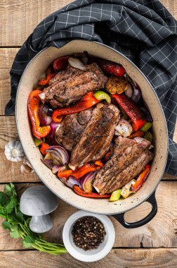 Roasted slow cooked lamb shanks with vegetables and herbs. Wooden background. Top view.