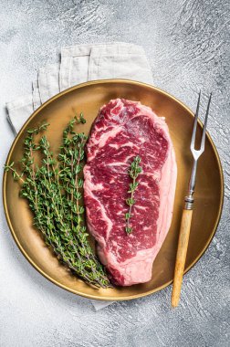 Uncooked Raw New York beef steak with thyme. White background. Top view.