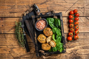Balık köftesi mi yoksa ıspanaklı ve şifalı otlu balık köftesi mi? Ahşap arka plan. Üst görünüm.