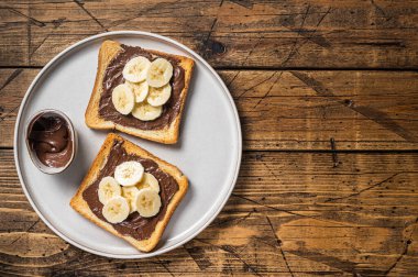 Cooking of sandwich with chocolate Hazelnut butter and bananas. Wooden background. Top view. Copy space.