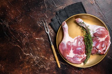 Raw duck legs. Poultry meat ready to cook. Dark background. Top view. Copy space.