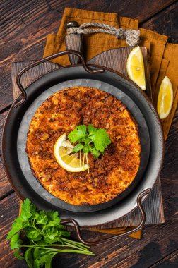 Traditional delicious Turkish foods lahmacun with mince lamb meat in steel tray. Wooden background. Top view.