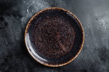 Masada boş siyah bir tabak var. Masa ayarı. Siyah arka plan. Üst Manzara. Boşluğu kopyala.