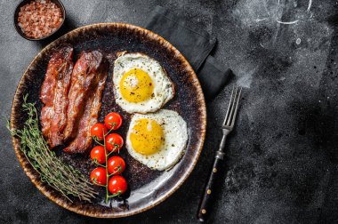 Yağda yumurta ve jambonlu kahvaltı tabakta otlar. Siyah arka plan. Üst Manzara. Boşluğu kopyala.