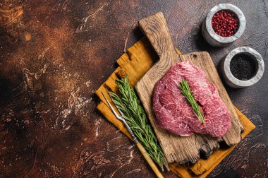 Uncooked Raw beef veal cheeks on wooden board. Dark background. Top view. Copy space.