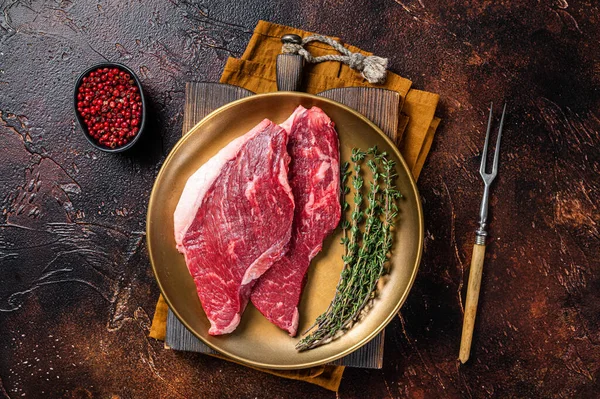 Freah Raw cap rump beef meat steak in a plate with thyme, top sirloin steak. Dark background. Top view.