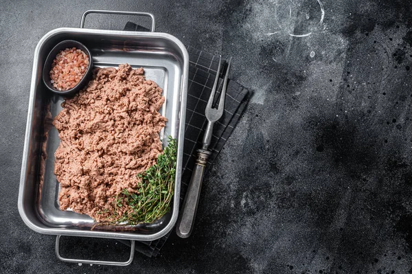 Vegetarian ground meat, raw plant based meat with herbs in kitchen tray. Black background. Top view. Copy space.