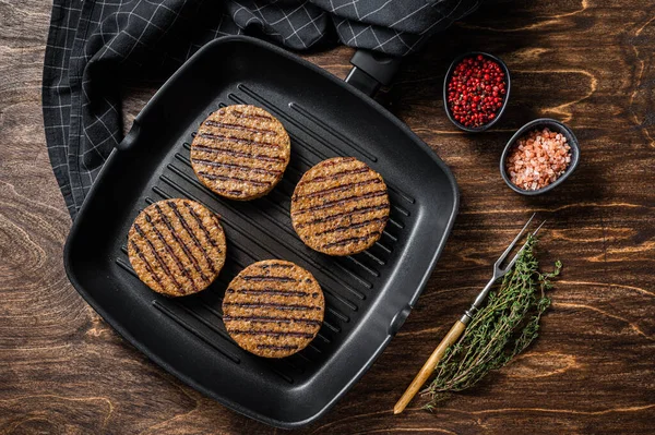 Grilled Vegetarian plant based meat burger patties, vegan cutlets on grill skillet. Wooden background. Top view.