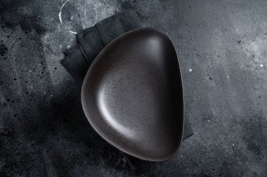 Masada boş siyah bir tabak var. Masa ayarı. Siyah arka plan. Üst Manzara. Boşluğu kopyala.