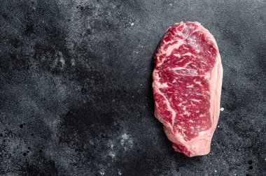 Raw Striploin steak, beef butchery cut. Black background. Top view. Copy space.