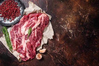 Unccoked marble black angus meat Steak on kitchen table, beef chuck roll steak. Dark background. Top view. Copy space.
