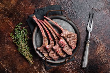 BBQ Grilled lamb chop steak, mutton rib cutlet in steel tray with thyme. Dark background. Top view.