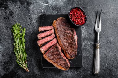 Mangalda sığır filetosu ya da mermer tahtada biftek. Siyah arka plan. Üst görünüm.
