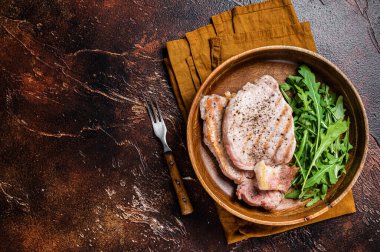 Roasted pork chop steaks or cutlets with arugula salad. Dark background. Top view. Copy space.