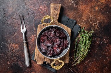 Ev yapımı geyik eti sosisi. Tavada otlar var. Karanlık arka plan. Üst görünüm.