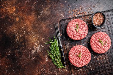 Raw burger cutlet from beef meat with spices and rosemary ready for cooking. Dark background. Top view. Copy space.