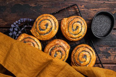 Sweet roll poppy seed buns with lavender ready for cooking. Wooden background. Top view.