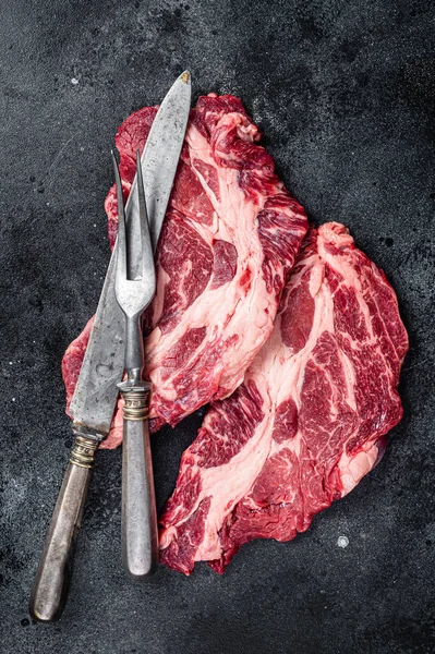 Fresh marbled meat Steaks with meat knife and fork table, beef rib eye steak. Black background. Top view.