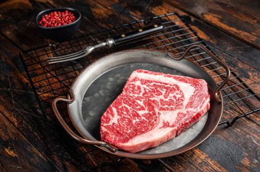 Raw wagyu rib eye beef meat steak in steel tray. Wooden background. Top view.