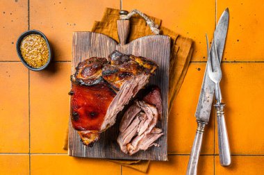 Roasted pork Shank, knuckle on a wooden board. Orange background. Top view.