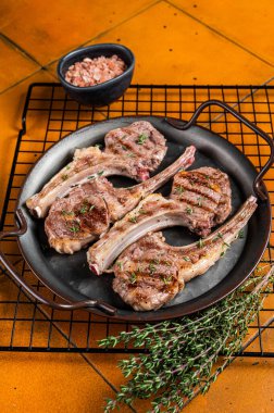 BBQ with Grilled lamb meat chops, mutton steaks with herbs. Orange background. Top view.