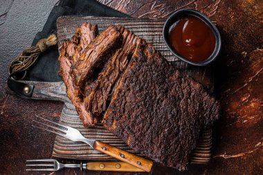 Traditional smoked barbecue wagyu beef brisket on wooden board. Dark background. Top view.