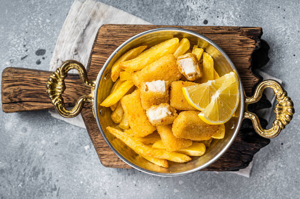 Рыбные пальцы и чипсы британский фаст-фуд с тартаром и томатным соусом, морепродукты. Серый фон. Вид сверху.