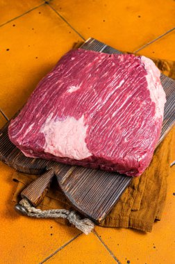 Whole piece of raw Beef Brisket meat. Orange background. Top view.