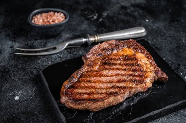 Grilled wagyu Rib Eye steak, marbled beef meat with salt. Black background. Top view.