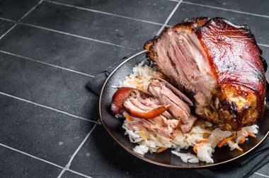Roast Pork Ham Hock, knuckle with Sauerkraut on a plate. Black background. Top view. Copy space.