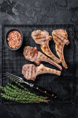 Barbecue Grilled lamb meat chops, mutton cutlets. Black background. Top view.