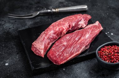 Bavette raw beef meat steak or Sirloin flap on marble board. Black background. Top view.