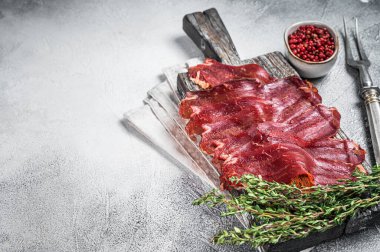 Pastirma Turkish sliced pastrami, dried beef meat with spices on wooden board. White background. Top view. Copy space.