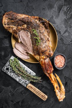 Christmas dish - Roast lamb leg meat with spices and thyme on a plate. Black background. Top view.
