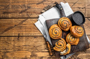 Poppy seed rolls and cardamom buns, Traditional Nordic baked sweet breads on wooden board. Wooden background. Top view. Copy space.