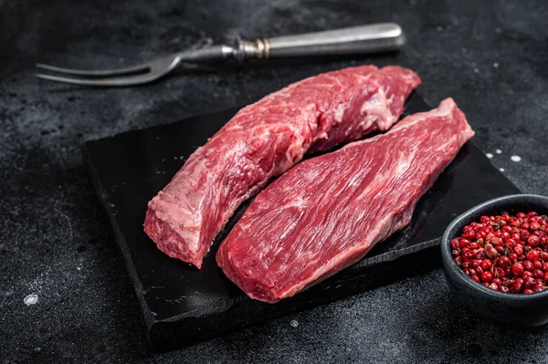 Bavette raw beef meat steak or Sirloin flap on marble board. Black background. Top view.