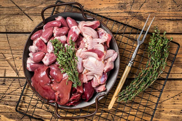 Raw bird giblets meat set, chicken offals, liver, hearts, gizzards Stomach. Wooden background. Top view.
