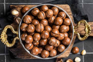 Macadamia nuts in a shell ready to eat. Black background. Top view.