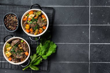 Beef bourguignon meat stew with vegetables, mushrooms and red wine in a pot. Black background. Top view. Copy space.