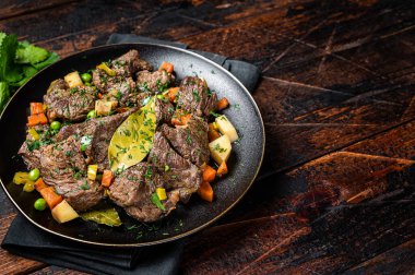 Beef meat stew, braised beef meat with vegetables in a plate. Wooden background. Top view. Copy space.