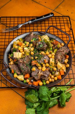 Spanish cocido Madrid stew with chickpeas, meat, carrots and potatoes. Orange background. Top view.