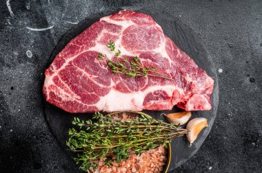 Pork loin steak, raw neck meat with thyme and salt. Black background. Top view.