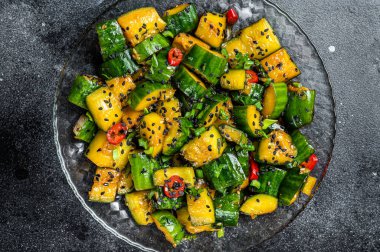 Chinese Chilled Pai Huang Gua Smashed Cucumber Salad with garlic, ginger, sesame oil, soy sauce. Black background. Top view.