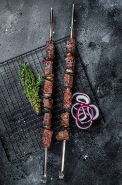 Cooked on the grill beef shish kebab with vegetables and spices, grileld meat. Black background. Top view.