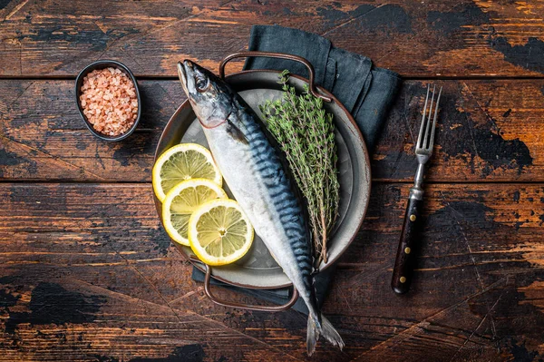 Uncooked mackerel fish, raw scomber with herbs. Wooden background. Top view.