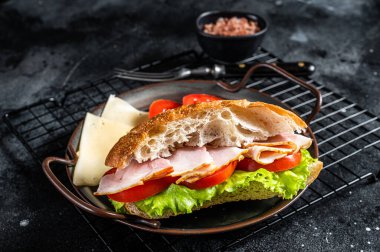 Deli meat sandwich with turkey ham, cheese, tomato and Lettuce. Black background. Top view.