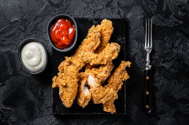 Breaded chicken strips Fingers with Ketchup. Black background. Top view.
