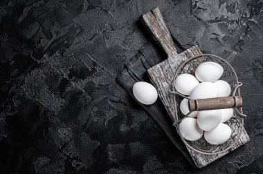 Basket with white chicken eggs. Black background. Top view. Copy space.