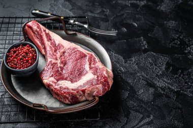 Dry aged Raw cowboy or rib eye steak. Black background. Top view. Copy space.